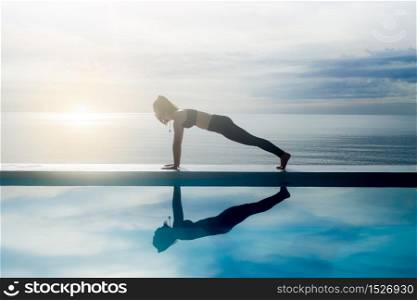 Vacation of Beautiful Attractive Asian young woman practice yoga Plank or Phalakasana Pose on the beach with beautiful sea,Feeling so comfortable and relax in holiday