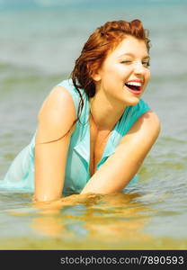 Vacation. Sensual girl wet cloth in water on the coast. Redhair woman having fun relaxing on the sea. Summertime.