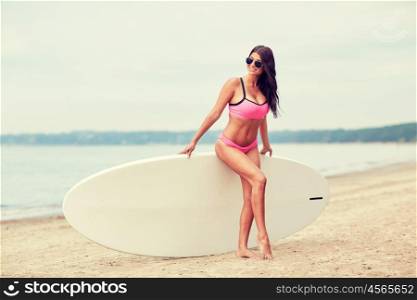 vacation, surfing, water sport and people concept - young woman in swimsuit with surfboard, windsurf or paddle board on summer beach