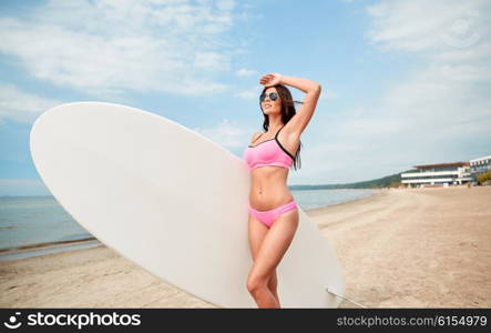 vacation, surfing, water sport and people concept - young woman in swimsuit with surfboard, windsurf or paddle board on summer beach