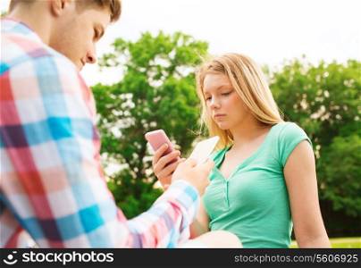 vacation, technology and friendship concept - couple with smartphones in park