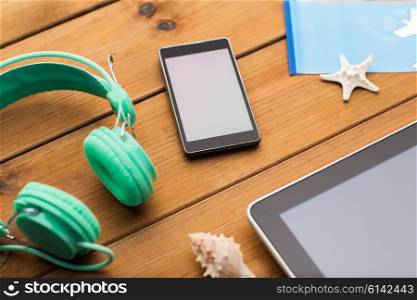 vacation, tourism, technology and objects concept - close up of smartphone, headphones and travel stuff
