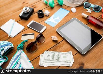 vacation, tourism, technology and objects concept - close up of tablet pc computer, dollar money and travel stuff