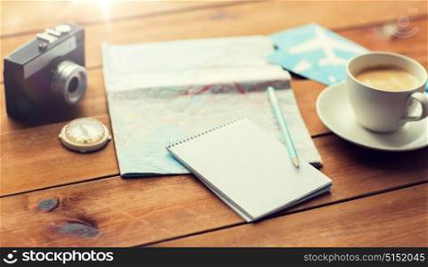 vacation, tourism, travel and objects concept - close up of blank notepad with map, coffee and airplane tickets. close up of notepad with map and travel tickets