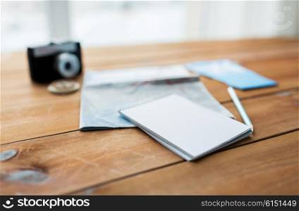 vacation, tourism, travel and objects concept - close up of blank notepad with map and airplane tickets