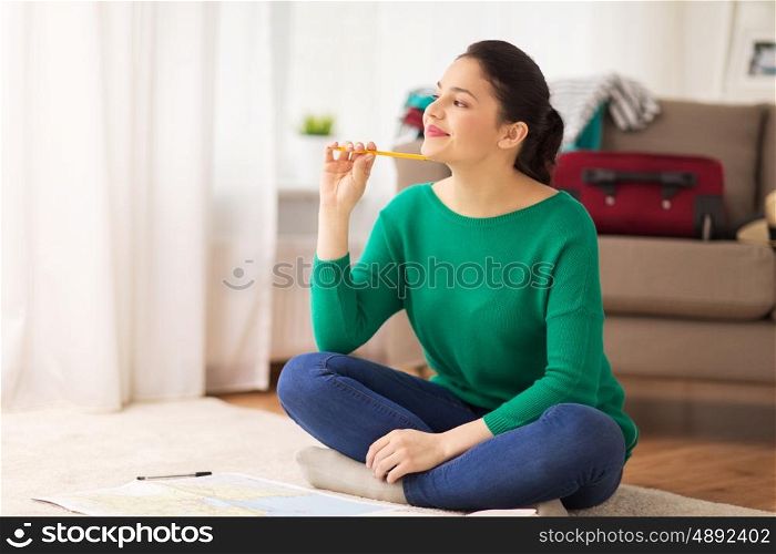 vacation, tourism, travel and people concept - happy young woman with map at home going on trip