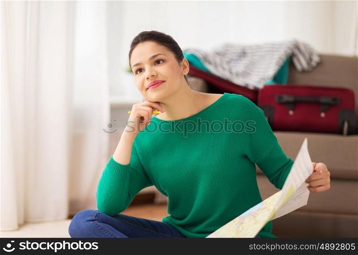 vacation, tourism, travel and people concept - happy young woman with map at home going on trip