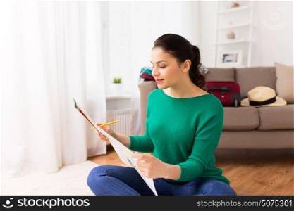vacation, tourism, travel and people concept - happy young woman with map at home going on trip. happy young woman with travel map at home