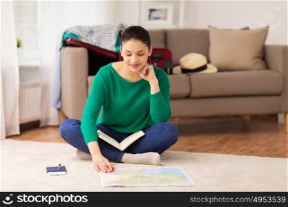 vacation, tourism, travel and people concept - happy young woman with notebook, passport and map at home going on trip. woman with notebook and travel map at home