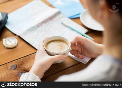 vacation, tourism, travel, destination and people concept - close up of hands with coffee cup and travel stuff