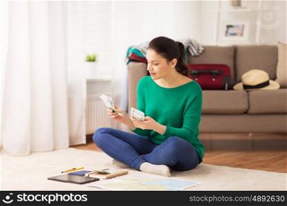vacation, tourism, travel, finances and people concept - happy young woman with money, tablet pc computer and map at home