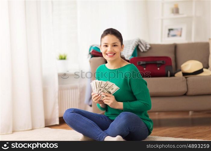 vacation, tourism, travel, finances and people concept - happy young woman with money and bag at home