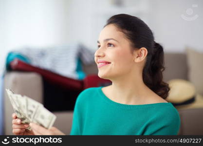 vacation, tourism, travel, finances and people concept - happy young woman with money at home. happy woman with money planning her travel at home
