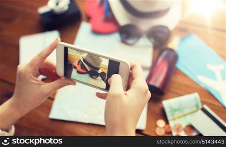 vacation, tourism, travel, technology and people concept - close up of woman with smartphone photographing map and travel stuff. close up of woman with smartphone and travel stuff