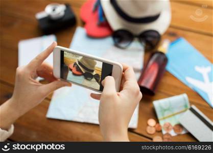 vacation, tourism, travel, technology and people concept - close up of woman with smartphone photographing map and travel stuff