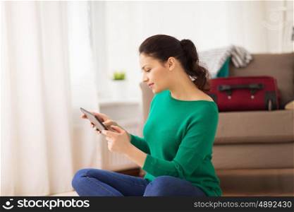 vacation, tourism, travel, technology and people concept - happy young woman with tabglet pc computer at home going on trip