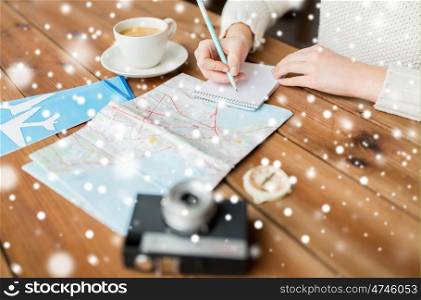 vacation, tourism, travel, winter holidays and people concept - close up of traveler hands with blank notepad and pencil