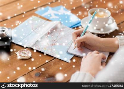 vacation, tourism, travel, winter holidays destination and people concept - close up of traveler hands with blank notepad and pencil