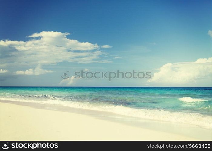 vacation, travel and background concept - blue sea or ocean, white sand and sky with clouds