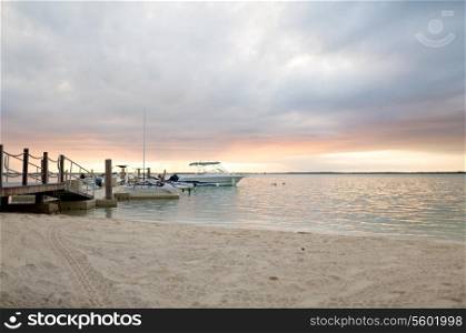 vacation, travel and sea concept - boats moored to pier at sundown