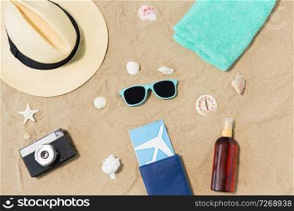 vacation, travel and tourism concept - air tickets in passport, vintage camera and hat and sunglasses on beach sand. travel tickets, camera and hat on beach sand