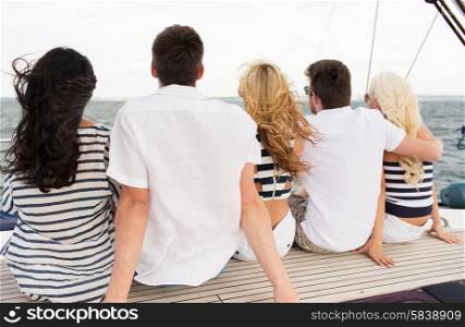 vacation, travel, sea, friendship and people concept - group of friends sailing and sitting on yacht deck