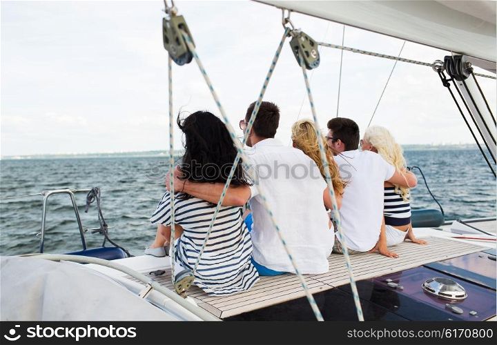 vacation, travel, sea, friendship and people concept - happy friends sailing and sitting on yacht or sail boat deck