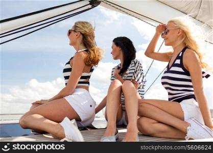 vacation, travel, sea, friendship and people concept - smiling girlfriends sitting on yacht deck