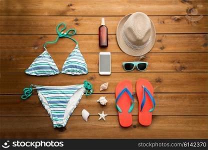 vacation, travel, tourism, technology and objects concept - close up of smartphone and beach stuff