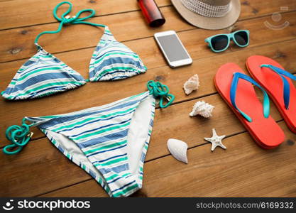 vacation, travel, tourism, technology and objects concept - close up of smartphone and beach stuff