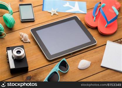 vacation, travel, tourism, technology and objects concept - close up of tablet pc computer and travel stuff