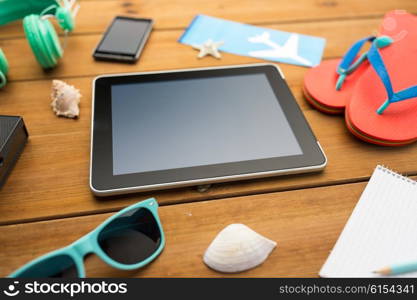 vacation, travel, tourism, technology and objects concept - close up of tablet pc computer and travel stuff