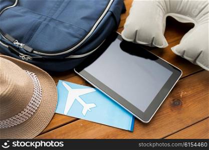 vacation, travel, tourism, technology and objects concept - close up of tablet pc computer and traveler personal stuff