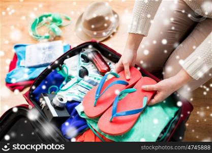 vacation, travel, tourism, winter holidays and objects concept - close up of woman packing bag with clothes and stuff