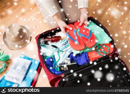 vacation, travel, tourism, winter holidays and objects concept - close up of woman packing bag with clothes and stuff