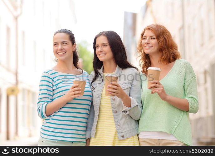 vacation, weekend, drinks and friendship concept - smiling teenage girls with coffee cups on street