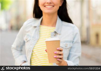 vacation, weekend, takeaway drinks, leisure and friendship concept - close up of happy young woman or teenage girl drinking coffee from disposable paper cups on city street