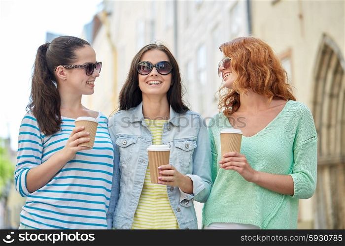 vacation, weekend, takeaway drinks, leisure and friendship concept - smiling happy young women or teenage girls drinking coffee from disposable paper cups on city street