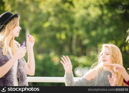Vacations joy, friendship concept. Women friends having fun blowing soap bubbles outdoor.. Women friends blowing soap bubbles.