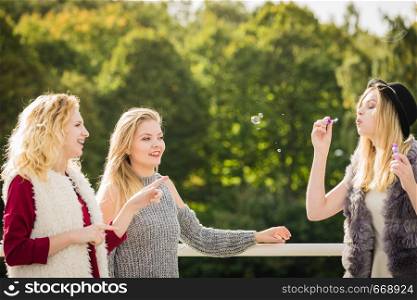 Vacations joy, friendship concept. Women friends having fun blowing soap bubbles outdoor.. Women friends blowing soap bubbles.