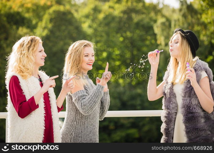 Vacations joy, friendship concept. Women friends having fun blowing soap bubbles outdoor.. Women friends blowing soap bubbles.