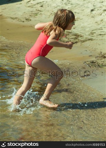 Vacations with kids concept. Little toddler girl playing on beach wearing swimsuit, having fun.. Little toddler girl playing on beach