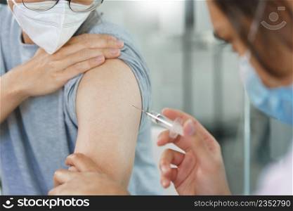 Vaccination concept, Male doctor in face mask injecting vaccine against covid-19 for male patient.