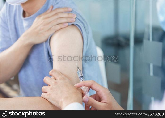 Vaccination concept, Male doctor in face mask injecting vaccine against covid-19 for male patient.