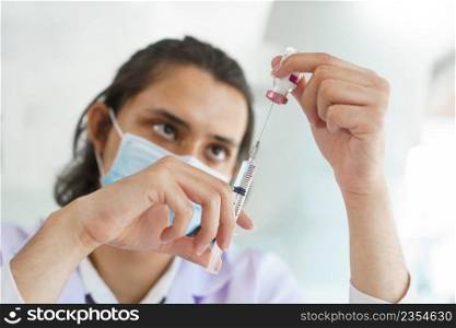 Vaccination concept, Male doctor in medical mask preparing vaccine against covid-19 for people.