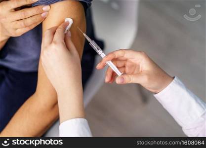 Vaccination healthcare concept - Hands of doctor or nurse hold a syringe and ampule preparing a shot of corona virus covid-19 hpv or flu vaccine for unknown patient arm - copy space close up