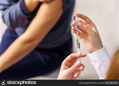 Vaccination healthcare concept - Hands of doctor or nurse hold a syringe and&ule preparing a shot of corona virus covid-19 hpv or flu vaccine for unknown patient - copy space close up