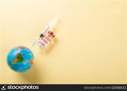 Vaccine vials bottles, syringes for vaccination against coronavirus and globe, medicine illness, COVID-19 disease vaccine isolated on yellow background