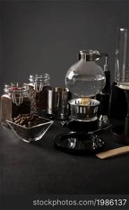 Vacuum coffee maker also known as vac pot, siphon or syphon coffee maker and toasted coffee beans on rustic black stone table. Copy space for your text