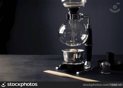 Vacuum coffee maker also known as vac pot, siphon or syphon coffee maker on rustic black stone table. Copy space for your text